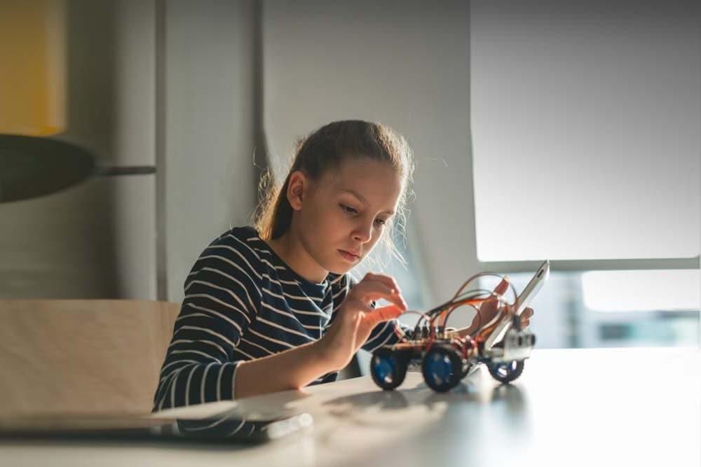 在五大湖学习学院的在线技术课上，年轻的女学生正在组装一辆机器人汽车